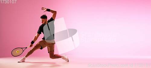 Image of Young caucasian man playing tennis isolated on pink studio background, action and motion concept