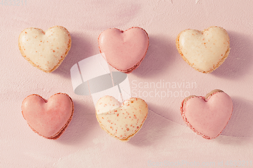 Image of Delicious French macarons in heart shape on pink background