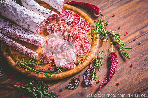 Image of Charcuterie - Assortment of air-dried salami and sausage on wooden cutting board with spices