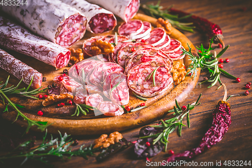 Image of Charcuterie - Assortment of air-dried salami and sausage on wooden cutting board with spices