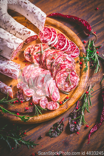 Image of Charcuterie - Assortment of air-dried salami and sausage on wooden cutting board with spices