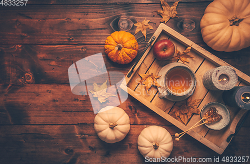 Image of Hot tea with cookies, apple and fall foliage and pumpkins on woo