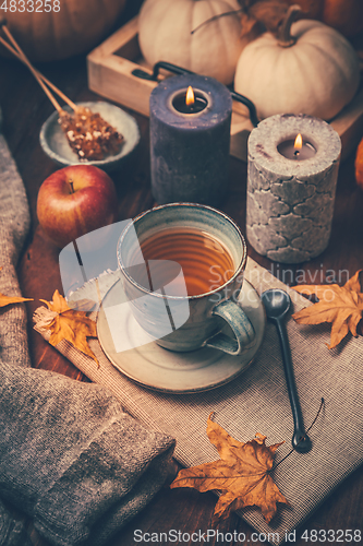 Image of Hot tea with cookies, apple and fall foliage and pumpkins on wooden background