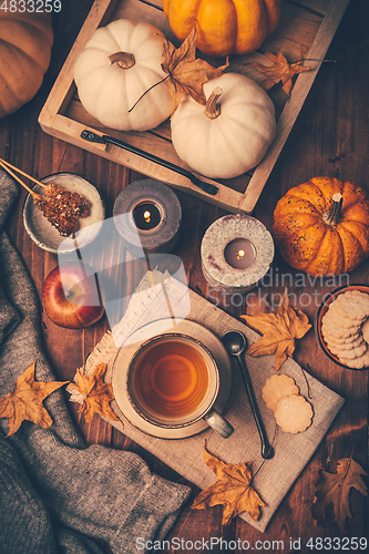 Image of Hot tea with cookies, apple and fall foliage and pumpkins on wooden background