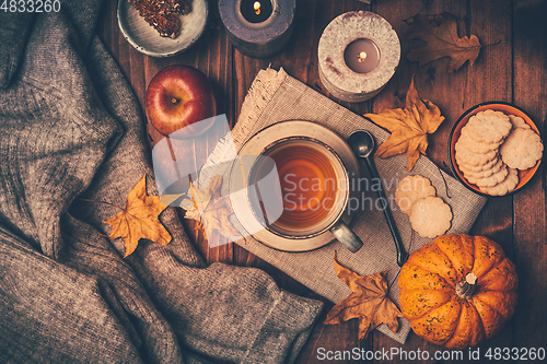 Image of Hot tea with cookies, apple and fall foliage and pumpkins on wooden background