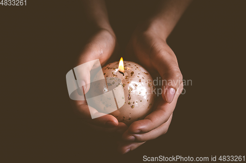 Image of Hands holding Christmas candle on dark background