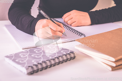 Image of Detail of hands writing with school supplies