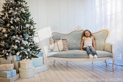 Image of Beautiful girl sitting on the sofa near christmas tree