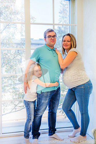 Image of Beautiful pregnant woman, girl and man near the window