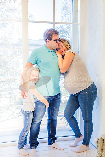 Image of Beautiful pregnant woman, girl and man near the window