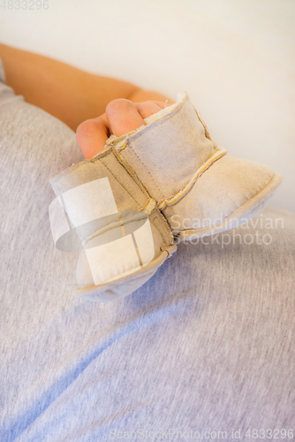 Image of Pregnant woman holding baby booties. Macro shot