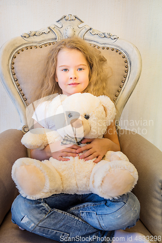 Image of Cute girl in casual clothes sitting in the armchair