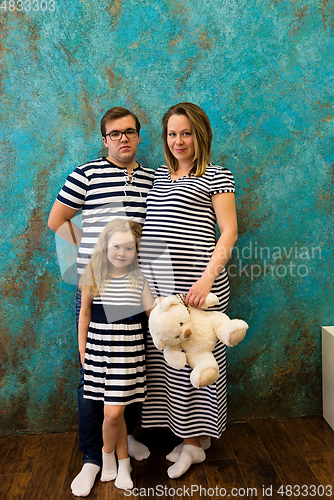 Image of Family portrait with pregnant woman, girl and man in striped clothes