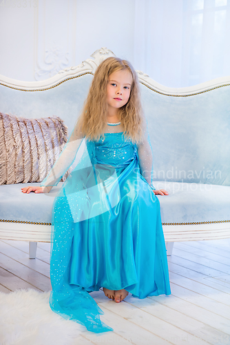 Image of Cute girl in a fancy dress sitting on the sofa