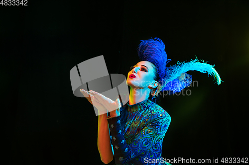 Image of Beautiful young woman in carnival and masquerade costume in colorful neon lights on black background