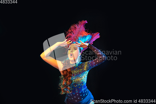 Image of Beautiful young woman in carnival and masquerade costume in colorful neon lights on black background