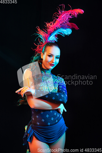 Image of Beautiful young woman in carnival and masquerade costume in colorful neon lights on black background