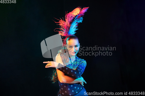 Image of Beautiful young woman in carnival and masquerade costume in colorful neon lights on black background