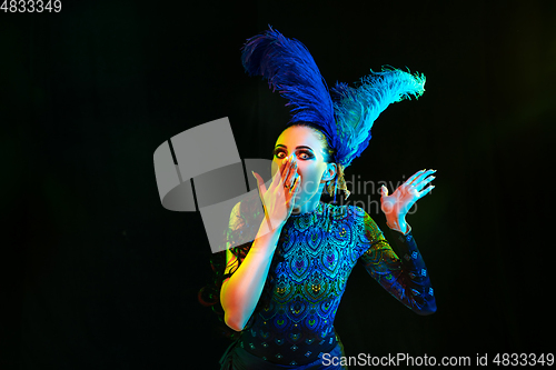 Image of Beautiful young woman in carnival and masquerade costume in colorful neon lights on black background