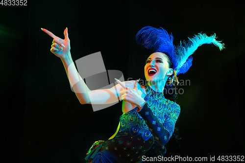 Image of Beautiful young woman in carnival and masquerade costume in colorful neon lights on black background