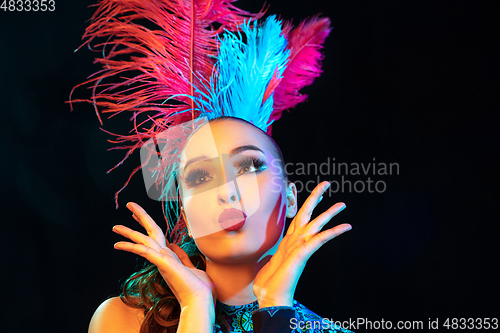 Image of Beautiful young woman in carnival and masquerade costume in colorful neon lights on black background