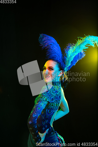 Image of Beautiful young woman in carnival and masquerade costume in colorful neon lights on black background