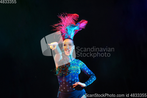 Image of Beautiful young woman in carnival and masquerade costume in colorful neon lights on black background