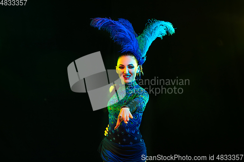 Image of Beautiful young woman in carnival and masquerade costume in colorful neon lights on black background