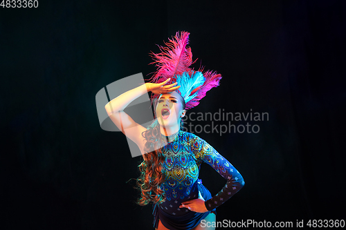 Image of Beautiful young woman in carnival and masquerade costume in colorful neon lights on black background