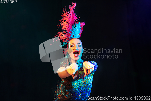 Image of Beautiful young woman in carnival and masquerade costume in colorful neon lights on black background