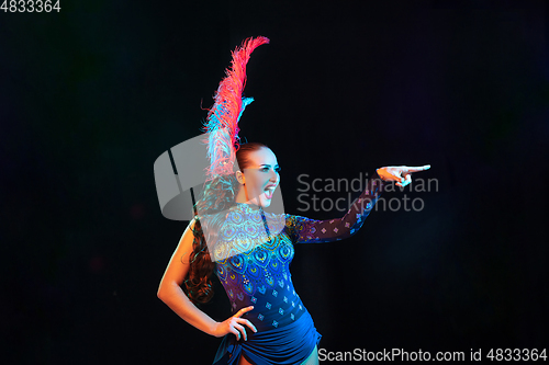 Image of Beautiful young woman in carnival and masquerade costume in colorful neon lights on black background