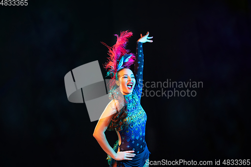 Image of Beautiful young woman in carnival and masquerade costume in colorful neon lights on black background