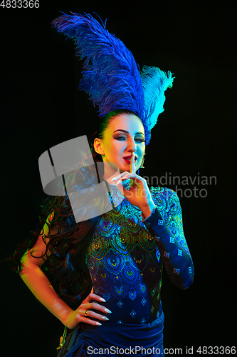 Image of Beautiful young woman in carnival and masquerade costume in colorful neon lights on black background