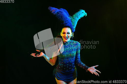 Image of Beautiful young woman in carnival and masquerade costume in colorful neon lights on black background