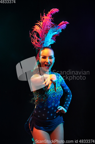 Image of Beautiful young woman in carnival and masquerade costume in colorful neon lights on black background