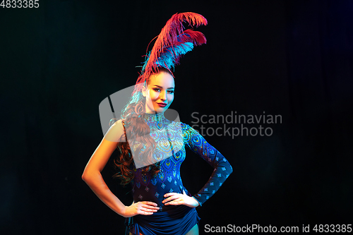 Image of Beautiful young woman in carnival and masquerade costume in colorful neon lights on black background