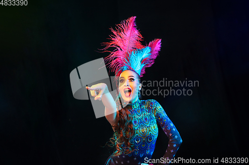 Image of Beautiful young woman in carnival and masquerade costume in colorful neon lights on black background