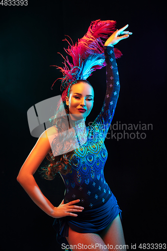 Image of Beautiful young woman in carnival and masquerade costume in colorful neon lights on black background