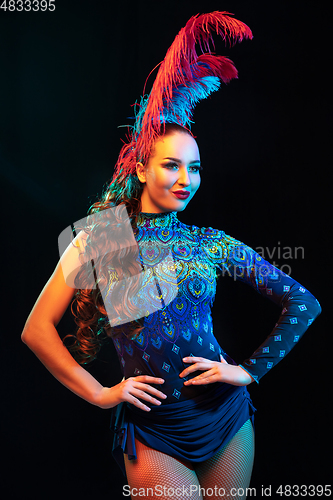 Image of Beautiful young woman in carnival and masquerade costume in colorful neon lights on black background