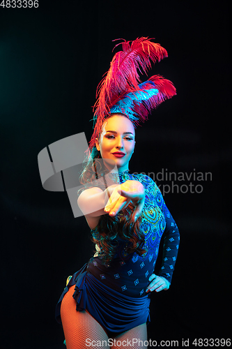 Image of Beautiful young woman in carnival and masquerade costume in colorful neon lights on black background