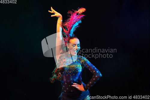 Image of Beautiful young woman in carnival and masquerade costume in colorful neon lights on black background