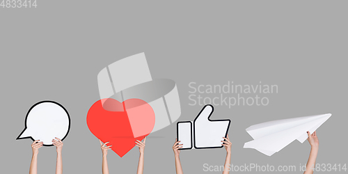 Image of Hands holding the signs of social media on grey studio background, flyer