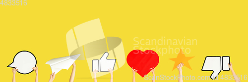 Image of Hands holding the signs of social media on yellow studio background, flyer