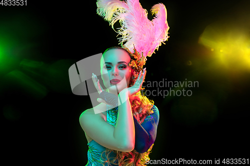 Image of Beautiful young woman in carnival and masquerade costume in colorful neon lights on black background