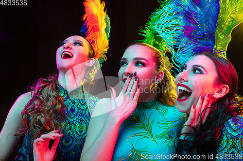 Image of Beautiful young women in carnival and masquerade costume in colorful neon lights on black background