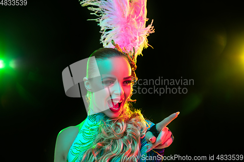 Image of Beautiful young woman in carnival and masquerade costume in colorful neon lights on black background