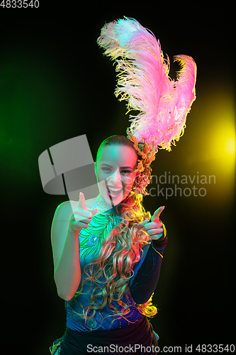 Image of Beautiful young woman in carnival and masquerade costume in colorful neon lights on black background