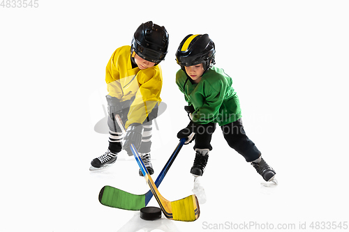 Image of Little hockey players with the sticks on ice court and white studio background