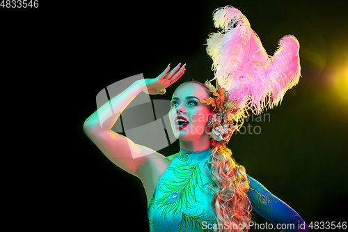 Image of Beautiful young woman in carnival and masquerade costume in colorful neon lights on black background