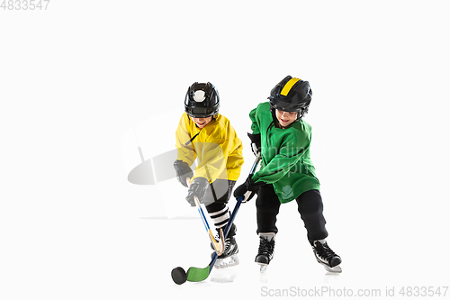 Image of Little hockey players with the sticks on ice court and white studio background